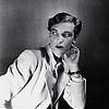 Black and white picture of a 30ish short-haired woman, wearing a white suit and lipstick.